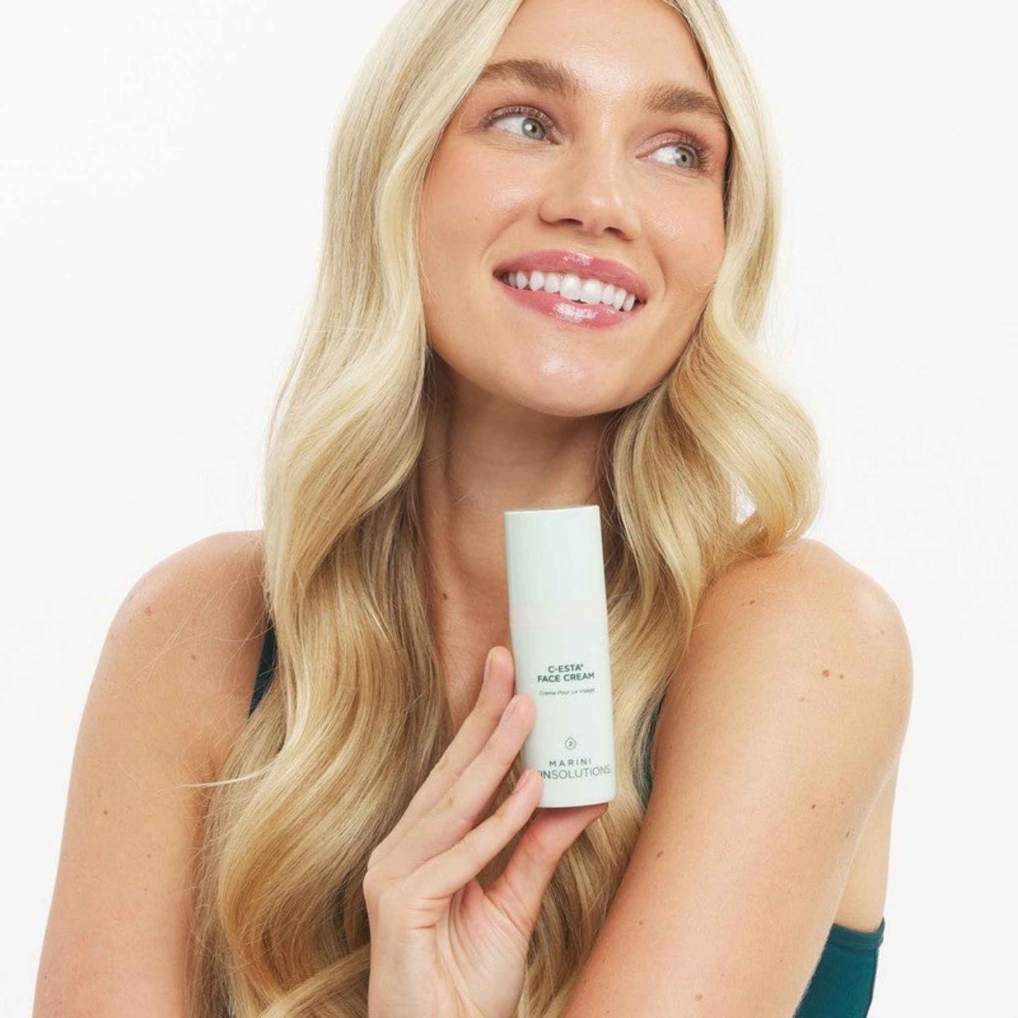Woman holding a Marini SkinSolutions C-ESTA Face Cream with a plain background