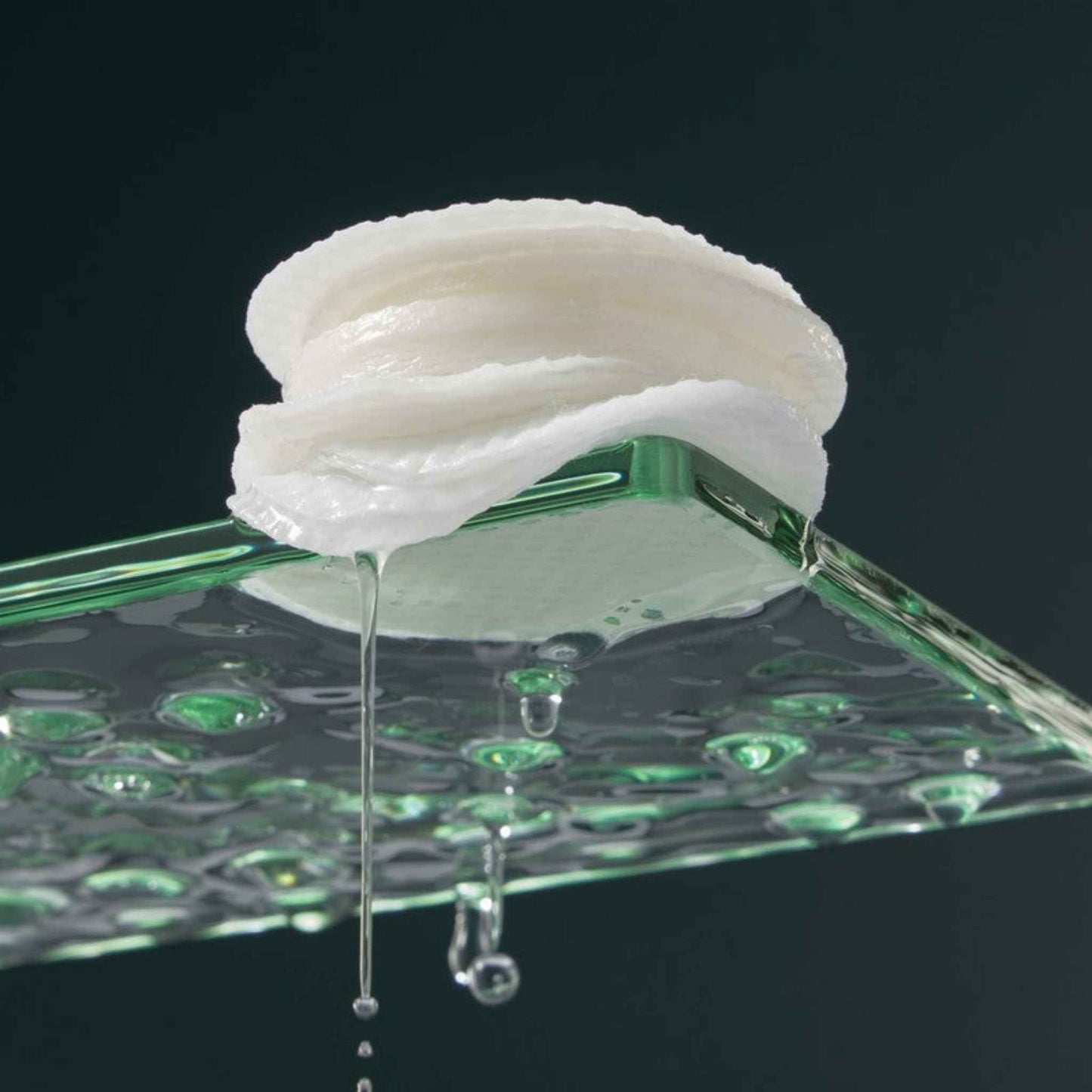 Marini SkinSolutions Resurface Peel Pads with droplets on a green glass surface against a black background