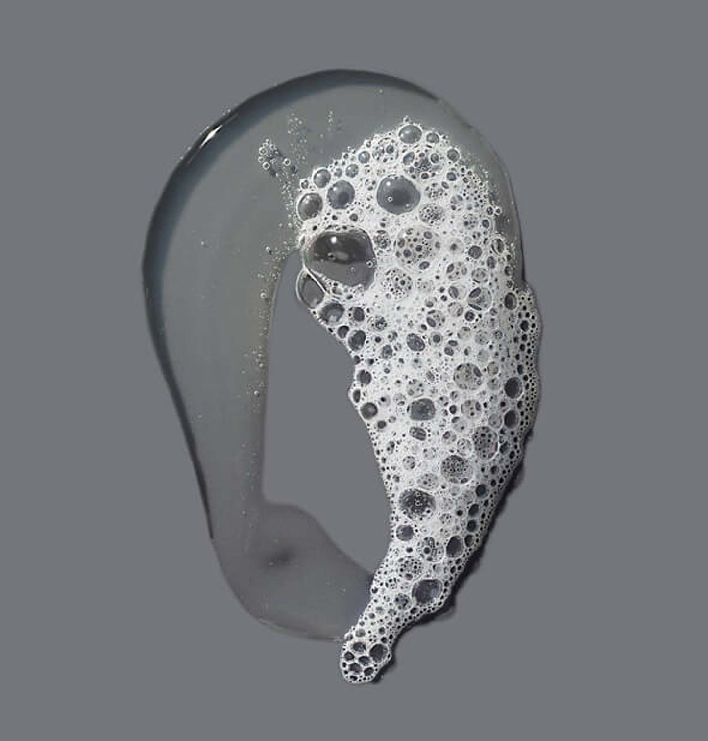 dermalogica conditioning body wash liquid with bubbles on a gray background